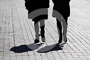 Silhouettes and shadows of two women walking down the street