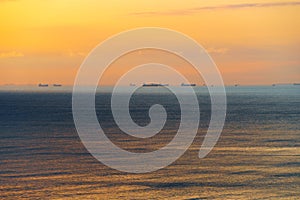 Silhouettes of ships at sea, dramatic seascape with sunset sky, sunlight reflected from the waves