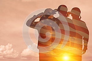 Silhouettes of soldiers with print of sunset and USA flag saluting on a background of light sky.