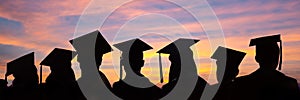 Silhouettes of students with graduate caps in a row on sunset background. Graduation ceremony web banner photo