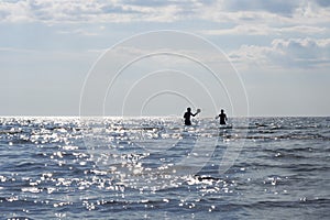 Silhouettes of sunbathers playing in the ocean photo