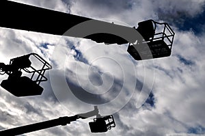 Silhouettes of three cranes against a blue cloudy sky