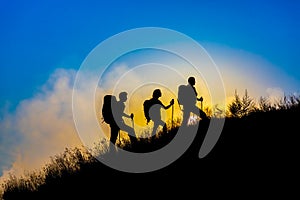 Silhouettes of three people walking with backpacks