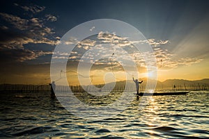 Silhouettes of the traditional fishermen throwing fishing net du