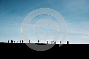 Silhouettes of travelers on the hill with blue sky