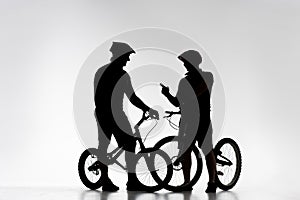 silhouettes of trial bikers with bicycles chatting