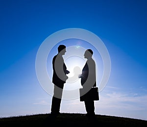 Silhouettes of Two Businessman Discussing Outdoors