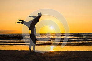 Silhouettes of two dancers doing acrobatics at sunset