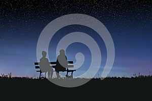 Silhouettes of two female friends sitting together and watching a spectacular night sky