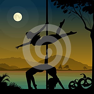 Silhouettes of two female pole dancers performing pole moves in front of river and full moon at Halloween night