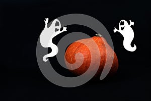 Silhouettes of two ghosts near a pumpkin against black background. Halloween concept photo