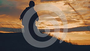 Silhouettes of two hikers with backpacks enjoying sunset view from top of a mountain. Enjoying the sunset view from