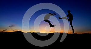 Silhouettes of two male fighters on sunset