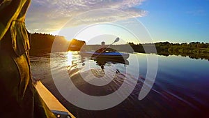 Silhouettes of two males kayaking at sunset, active rest, slowmo