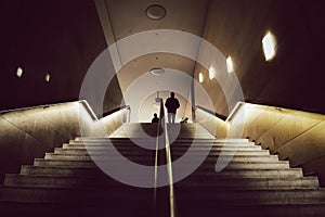 Silhouettes of two men meeting on top of mysterious wide stairs.