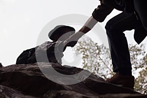 Silhouettes of two people climbing on mountain and helping, Help