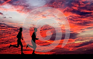 Silhouettes of two runners on fiery background