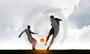 Silhouettes of two soccer players