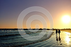 Silhouettes of Two Women walking on the Shores of Venice Beach at Sunset - Los Angeles, California