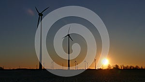 Silhouettes of wind turbines against sunset sky