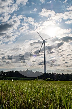 Silhouettes of wind turbines on a green agrarian farm field against dramatic clouds before the storm