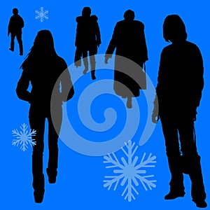 Silhouettes of women outdoors in warm clothes in winter walking on a pedestrian street.