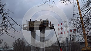 Silhouettes of workers-installers  working on a column, a support for an automobile overpass under construction