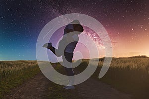 Silhouettes of a young couple in love under the starry sky with milky way