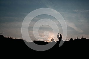 Silhouettes of a young couple lovers at sunset on dramatic sky background. Place for text or advertising