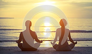 Silhouettes of a young couple sitting in the yoga Lotus position