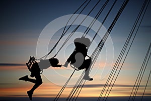 Silhouettes of young girls having fun on carousel photo