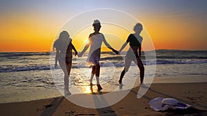 Silhouettes of young group of people jumping in ocean at sunset
