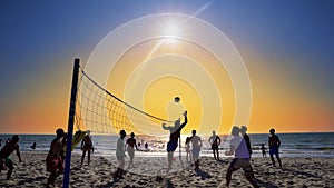 Silhouettes of young men playing volleyball on Varkala beach at sunset