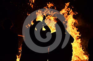 Silhouettes young people around roaring flames fire bonfire photo