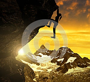 Silhoutte of girl climbing on rock at sunset