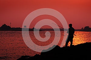 Silhoutte of a man fishing photo