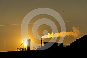 Silhuette Industrial factory smoke from smokestacks over colorful sunset sky industry