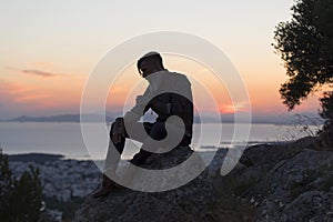 Silhuette of a man with a beard sitting on a rock