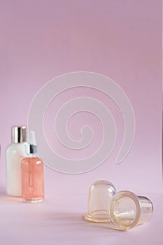 Silicon vacuum cuppings and defocused mochup bottles, woman body and skincare things, items for cellulite, on pink empty photo