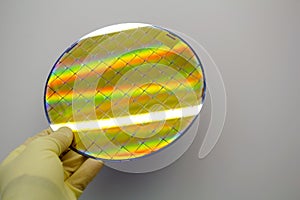 Silicon Wafer is held in the hands by gloves - A wafer is a thin slice of semiconductor material, such as a crystalline silicon, photo