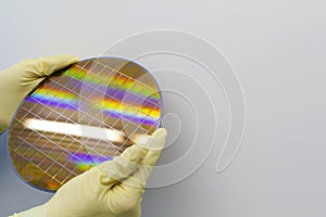 Silicon Wafer is held in the hands by gloves - A wafer is a thin slice of semiconductor material, such as a crystalline silicon,