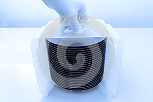 Silicon wafer inspection. A batch of silicon wafers packed in a plastic storage box in the clean room of a semiconductor