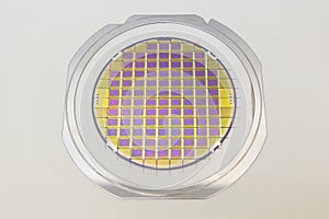 Silicon wafer with microchips fixed in the holder with steel frame on the grey background and ready for process photo