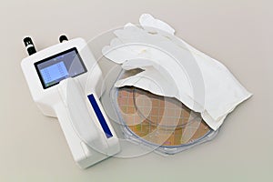 Silicon Wafer in plastic holder box on a table with particle counter near