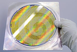 Silicon Wafer in steel holder helds by hand in gloves - A wafer is a thin slice of semiconductor material, such as a crystalline