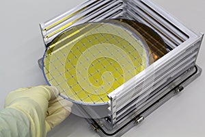 Silicon Wafers in steel holder box take out by hand in gloves- A wafer is a thin slice of semiconductor material, such as a