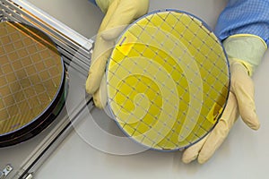 Silicon Wafers in steel holder box take out by hand in gloves- A wafer is a thin slice of semiconductor material, such photo