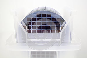 Silicon Wafers in white plastic holder box on a table- A wafer is a thin slice of semiconductor material, such as a