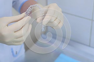 Silicone invisible transparent braces in orthodontist doctor hands in dentistry.