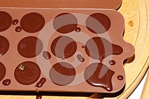 Silicone molds for shaping chocolate and sweets are filled with hot chocolate to cool